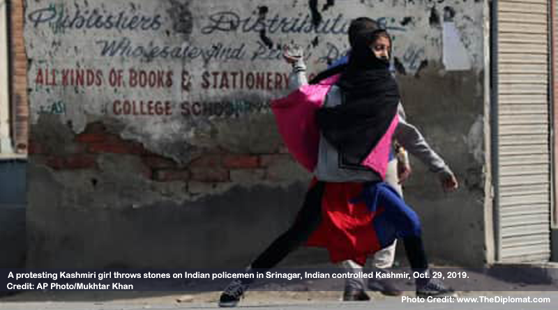 A protesting Kashmiri girl throws stones on Indian policemen