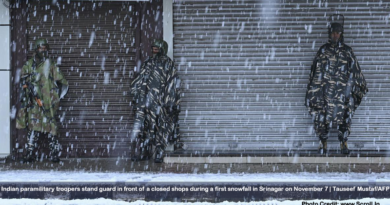 Indian paramilitary troopers stand guard in front of a closed shops during a first snowfall in Srinagar on November 7.