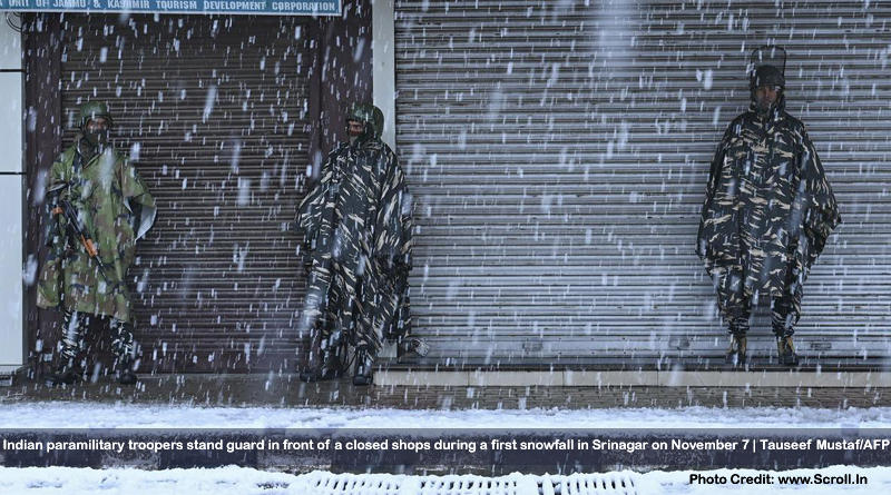 Indian paramilitary troopers stand guard in front of a closed shops during a first snowfall in Srinagar on November 7.