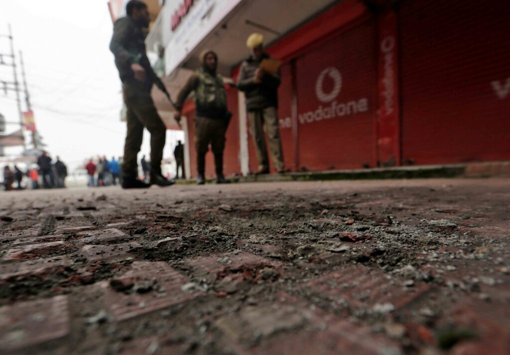 Policemen stand guard at the site of a grenade explosion in Srinagar on November 26