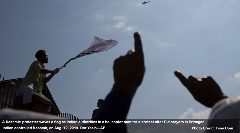 A Kashmiri protester waves a flag as Indian authorities in a helicopter monitor a protest after Eid prayers in Srinagar, Indian controlled Kashmir, on Aug. 12, 2019. Dar Yasin—AP