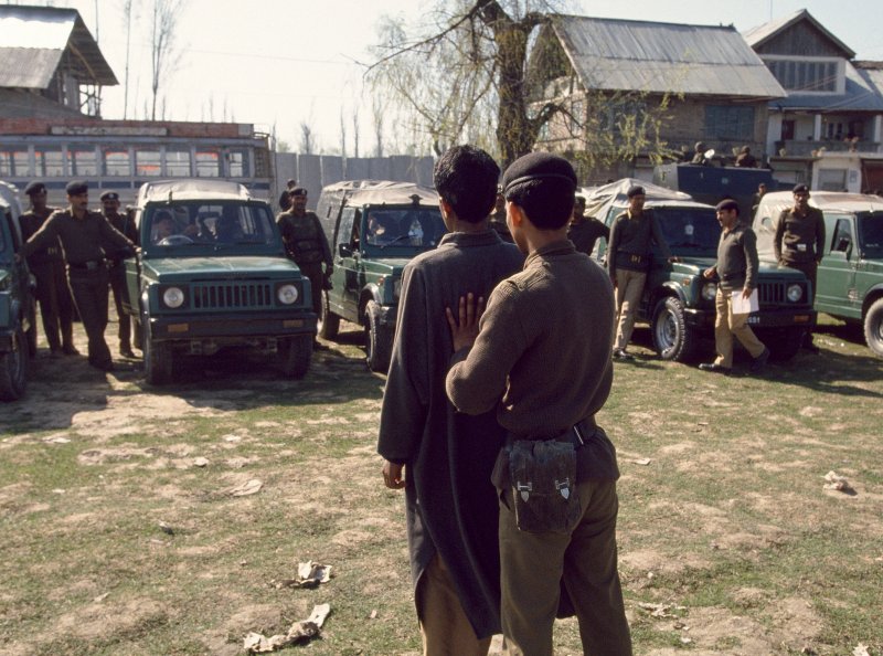 An Indian Border Security Force soldier shows a suspected militant to people in a line of parked military vehicles, Srinagar, India, on July 28, 1994. Robert Nickelsberg—Getty Images